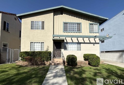 A beige house with a green awning and a white fence.