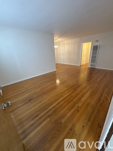 A room with wooden flooring and a rug in the middle.