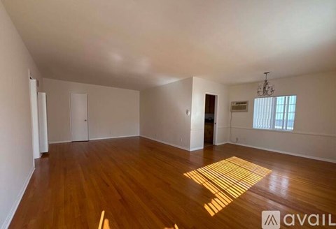 A room with wooden flooring and a rug in the middle.
