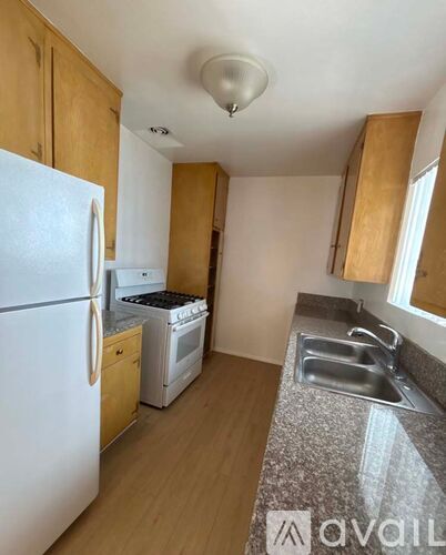 A kitchen with a white fridge, stove, and sink.