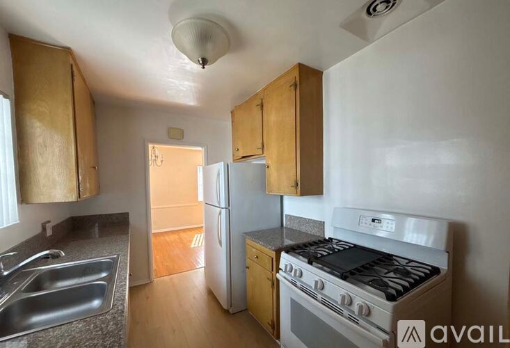 A kitchen with a stove, sink, and refrigerator.