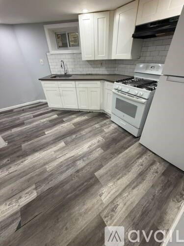 A kitchen with white cabinets and a wood floor.