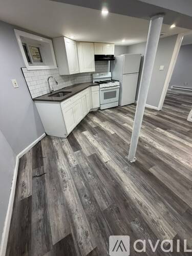A kitchen with white cabinets and a wooden floor.