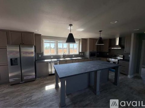 A kitchen with a large island in the middle and a refrigerator on the left.