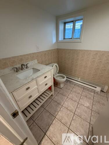 A bathroom with a sink, toilet, and a window.