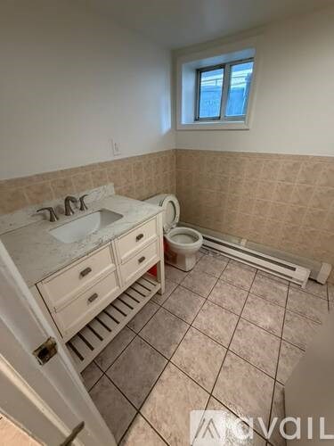 A bathroom with a sink, toilet, and a window.