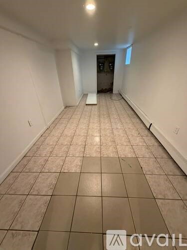 A long hallway with tiled floors and white walls.