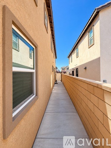 A narrow alley with a wall on one side and a building with a window on the other.