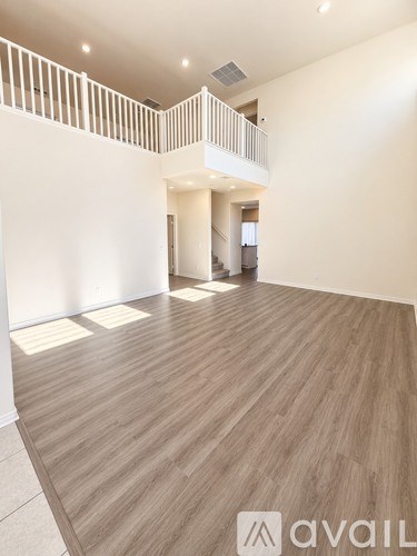 A spacious room with wooden flooring and a balcony.