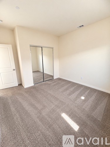 A carpeted room with a sliding door and a white door.