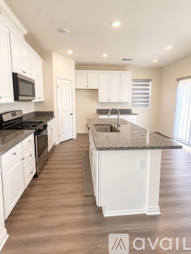 A kitchen with white cabinets and a granite countertop.