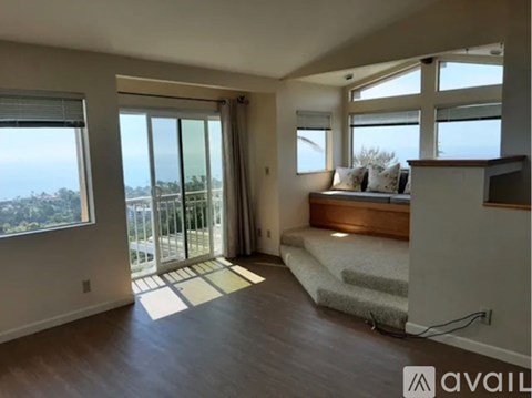 A bedroom with a large bed and a balcony overlooking the ocean.