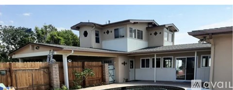A house with a white and beige exterior and a brown fence.
