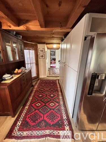 A kitchen with a rug on the floor and a refrigerator on the right.