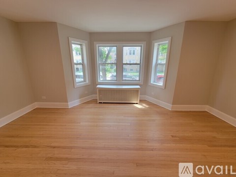 A room with wooden floors and two windows.
