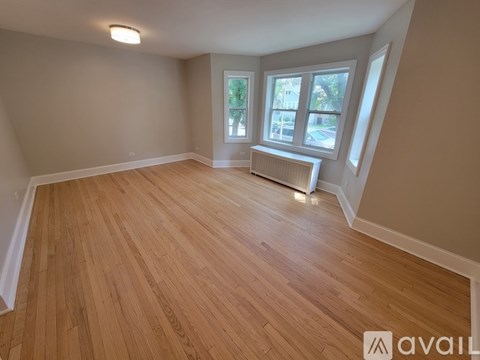 A room with wooden flooring and a window with a view of a street.