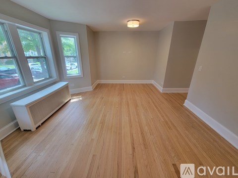 A room with wooden flooring and a window with a view of the street.
