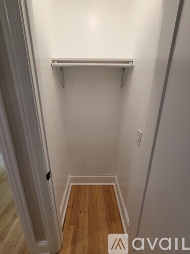 A white closet with a wooden floor and a white door.