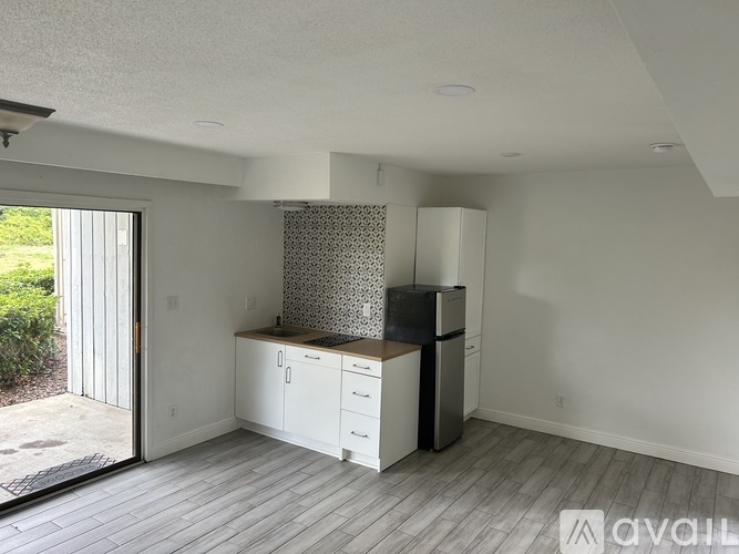 A kitchen with white cabinets and a black refrigerator is available.