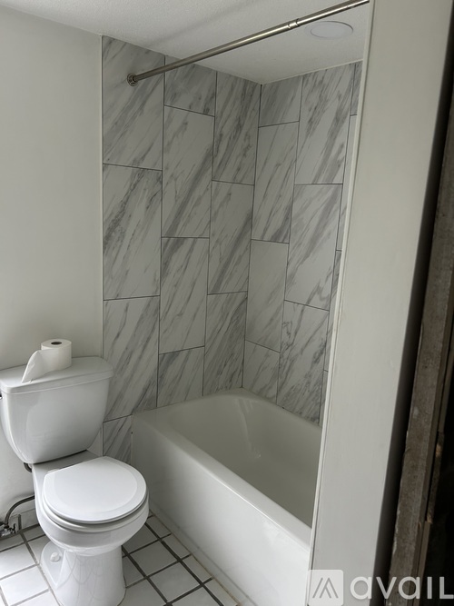 A white toilet sits next to a bathtub in a bathroom.