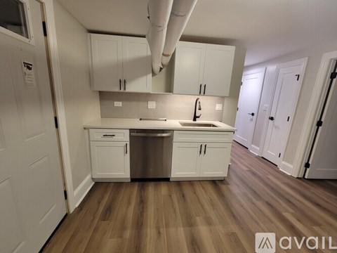 A kitchen with white cabinets and a wooden floor.