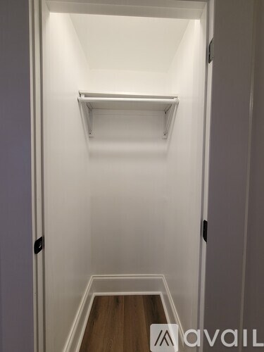 A white door with a shelf above it and a wooden floor below.
