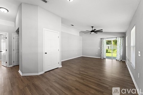 A spacious room with wooden flooring and a ceiling fan.