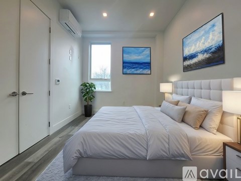 A bedroom with a large bed and a painting of a wave on the wall.