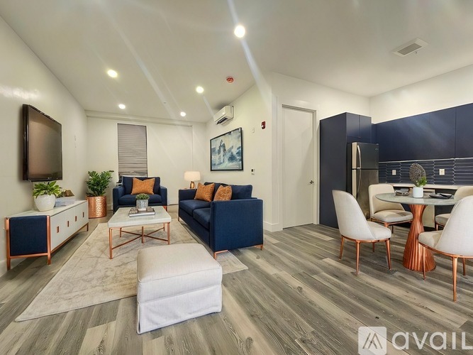A living room with a white sofa, a white coffee table, and a TV on the wall.