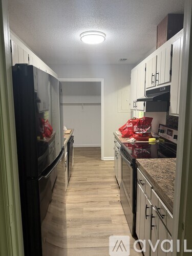 A kitchen with a black refrigerator and wooden floors.