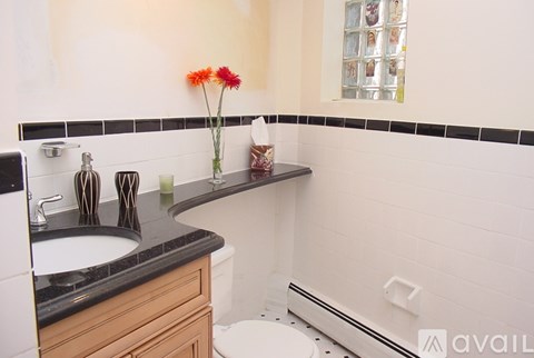 A bathroom with a sink, toilet, and a vase of flowers.