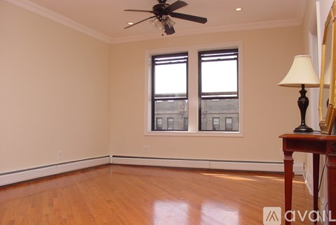 A room with a ceiling fan and a table with a lamp on it.