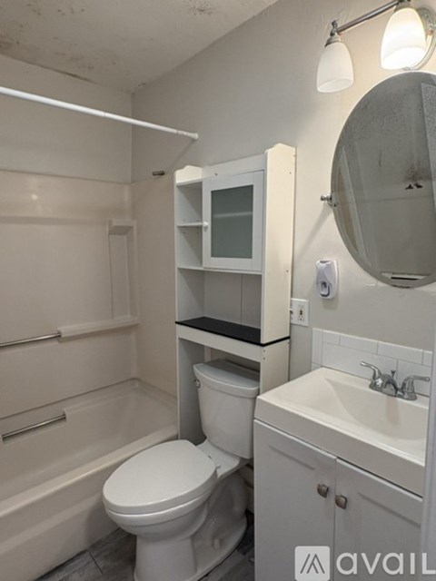A white bathroom with a toilet, sink, and mirror.