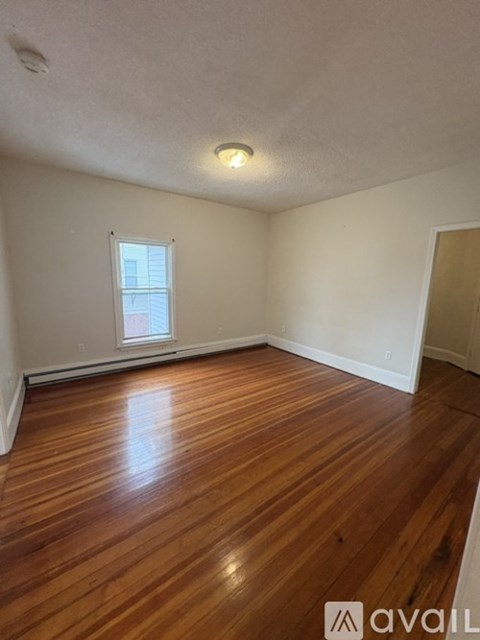 A room with wooden flooring and a window.