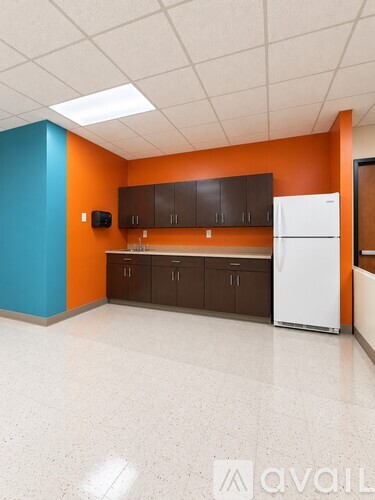 A kitchen with orange walls and a white refrigerator.