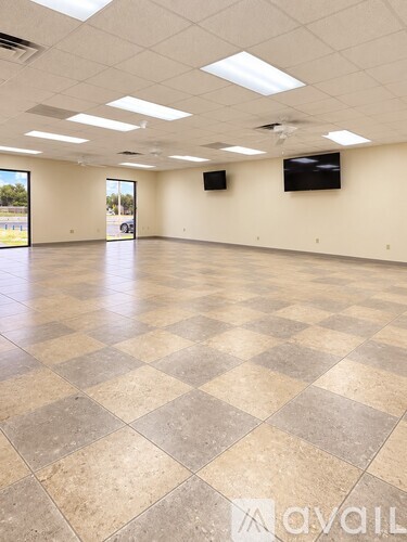 A spacious room with a checkered floor and two televisions on the wall.