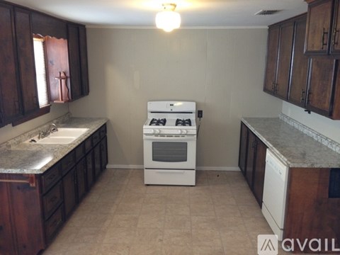 A kitchen with a white stove and dark wood cabinets.