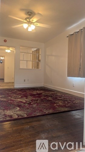 A room with a ceiling fan and a rug on the floor.
