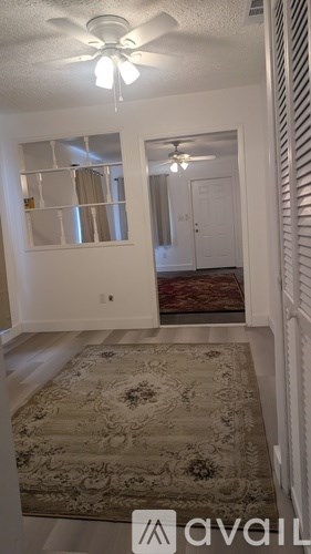 A hallway with a rug on the floor and a ceiling fan.