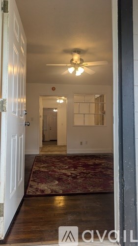 A hallway with a rug and a ceiling fan.