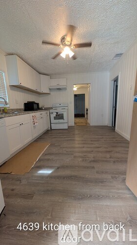 A kitchen with white cabinets and a wooden floor.