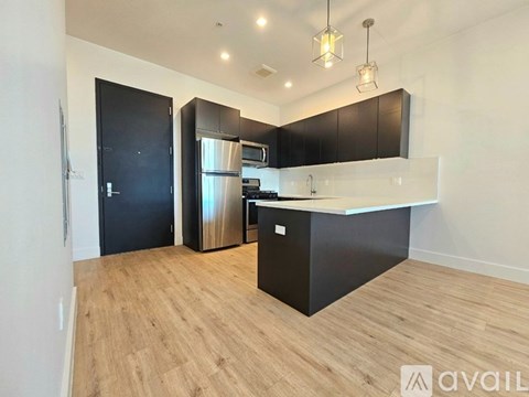 A kitchen with black cabinets and a wooden floor.