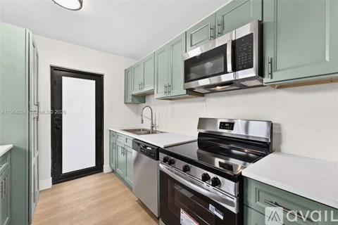 A kitchen with green cabinets and stainless steel appliances.