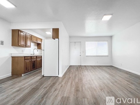 A kitchen with wooden cabinets and a white refrigerator in a room with wooden flooring.
