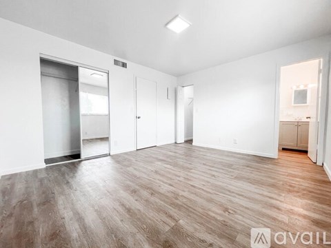 A spacious room with wooden flooring and white walls.