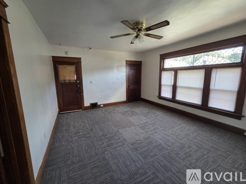 A room with a ceiling fan and carpeted floor.