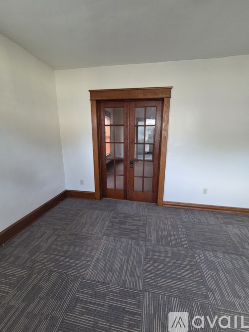 A room with a carpeted floor and a wooden door.