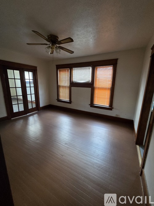 A room with a ceiling fan and wooden flooring.