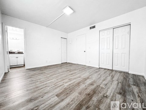 A spacious room with wood flooring and white walls.