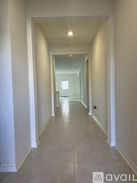 A long hallway with white walls and tile flooring.
